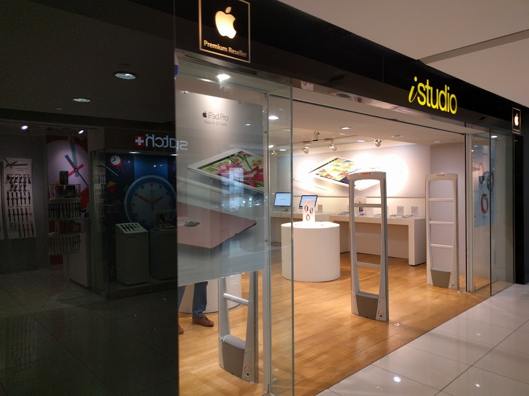 The glass storefront of iStudio, an Apple Premium Reseller, showcasing Apple products and a modern interior.