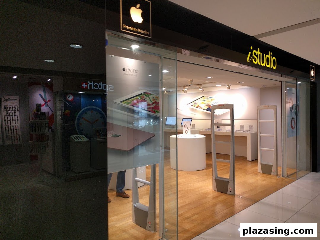 The glass storefront of iStudio, an Apple Premium Reseller, showcasing Apple products and a modern interior.