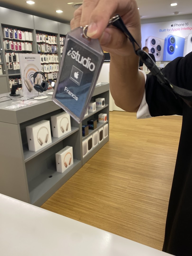 An iStudio staff member's name tag with Apple products and displays in the background.