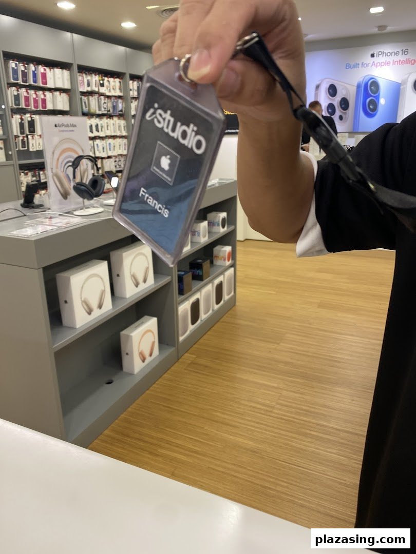 An iStudio staff member's name tag with Apple products and displays in the background.