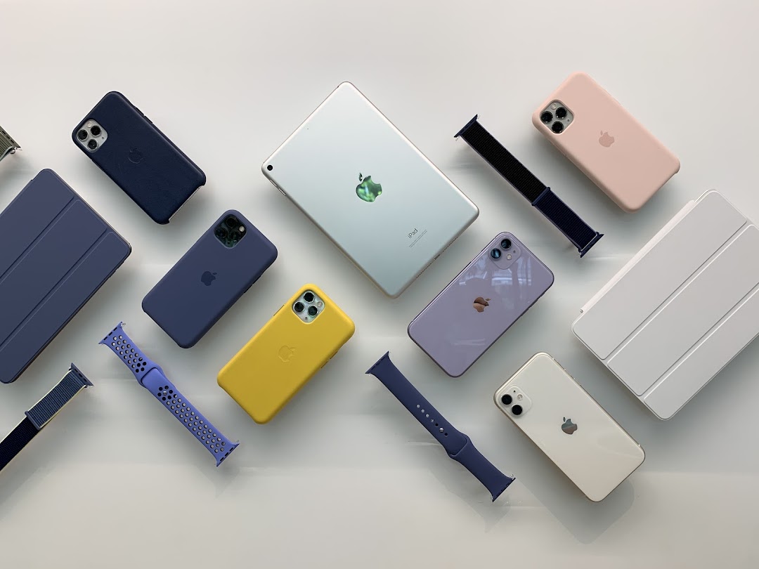 A flat lay of various Apple products including iPhones, an iPad, cases, and watch bands.