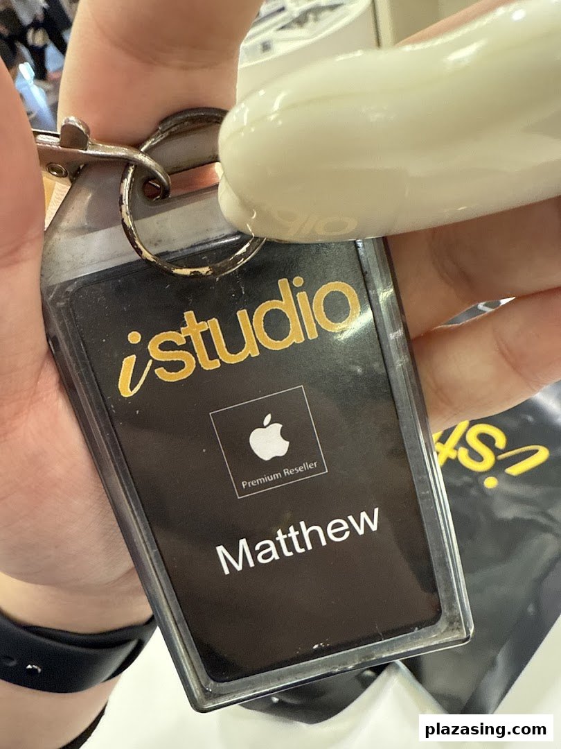 Close-up of an iStudio Apple Premium Reseller keychain/ID tag held by a hand.