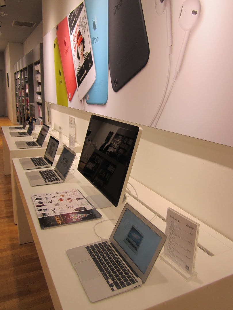 Modern iStudio interior showcasing Apple products like MacBooks, iMacs, and iPods on display.