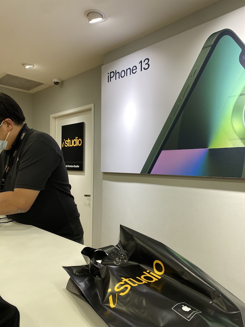 Interior view of iStudio featuring an iPhone 13 display, staff, and a branded shopping bag.