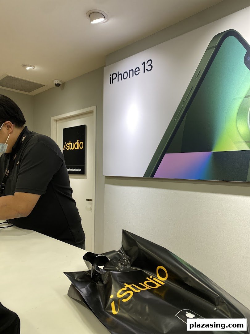 Interior view of iStudio featuring an iPhone 13 display, staff, and a branded shopping bag.