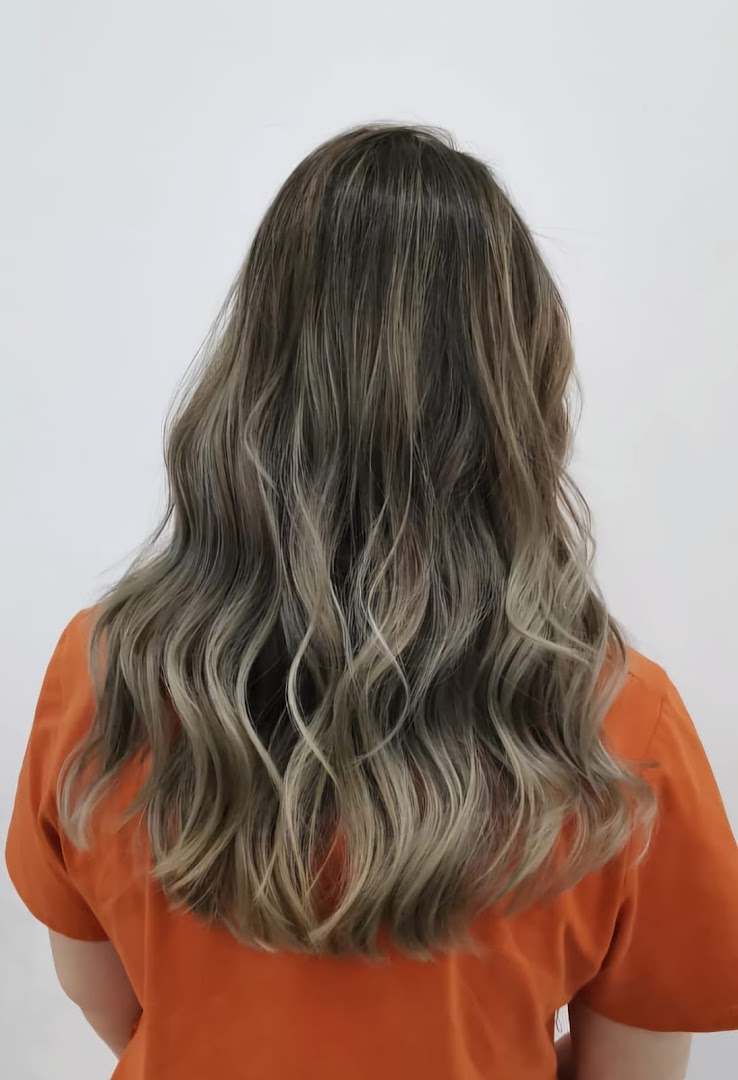 Back view of a person showcasing long, wavy hair with blonde and brown highlights.