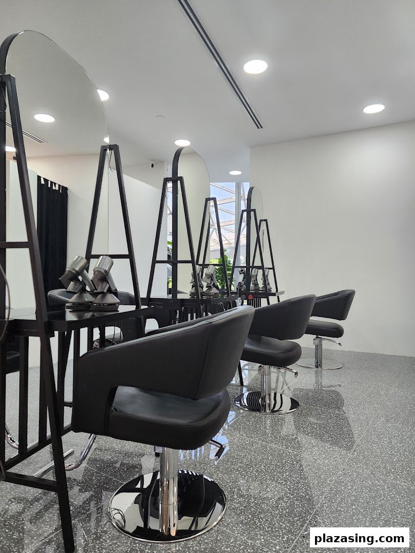 A modern hair salon interior featuring multiple styling stations with black chairs and large mirrors.