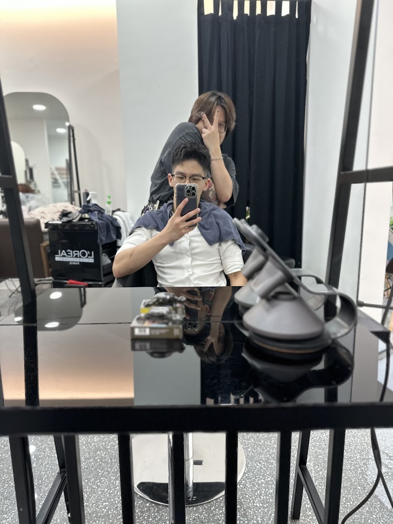 A stylist poses behind a client taking a mirror selfie inside J Hair Salon.