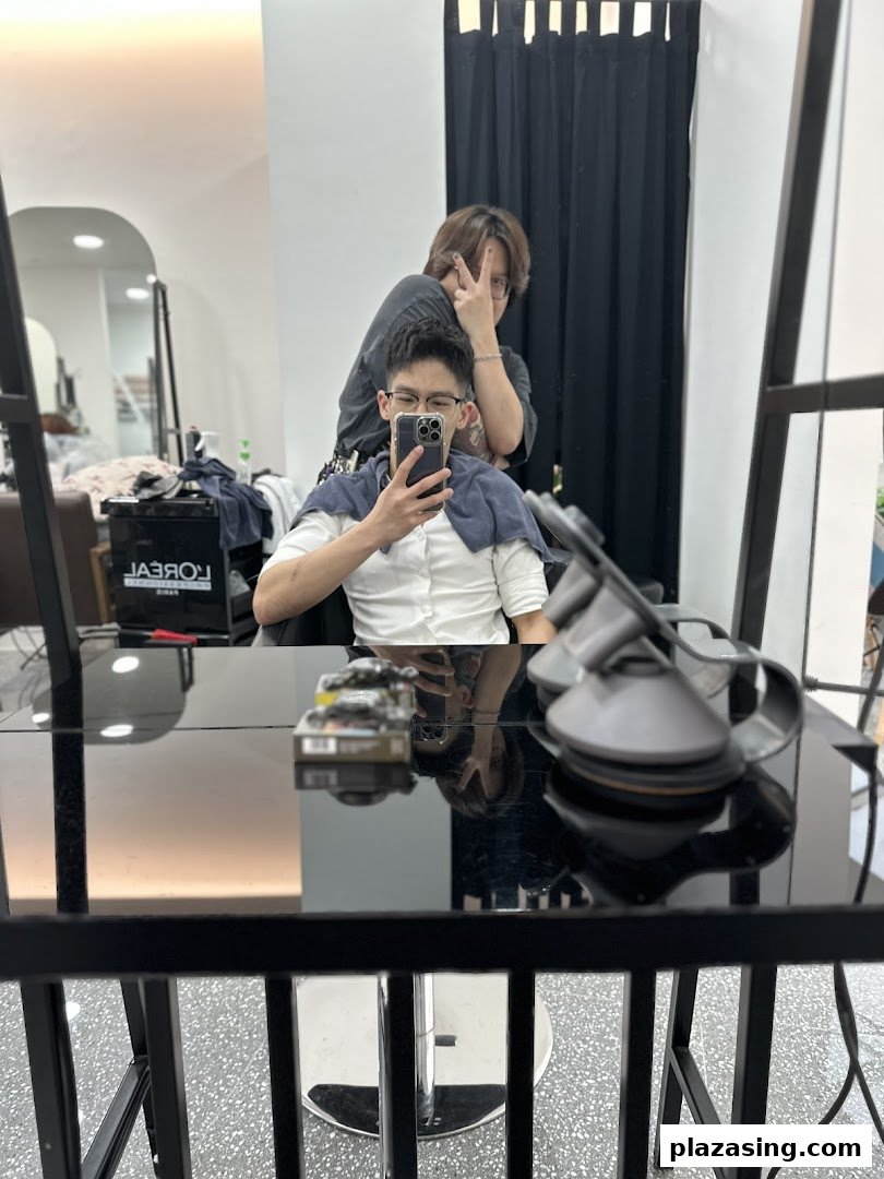 A stylist poses behind a client taking a mirror selfie inside J Hair Salon.