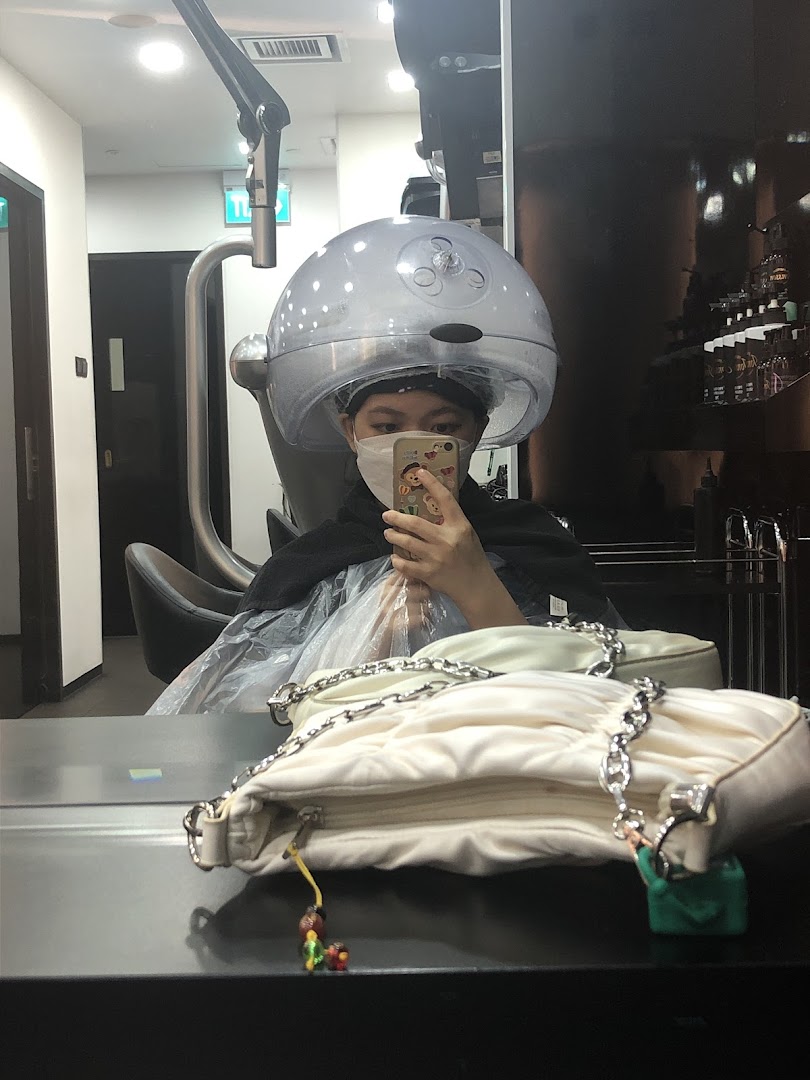 A person in a face mask is reflected in a mirror, undergoing a hair treatment with a steamer at Jonsson Protein.