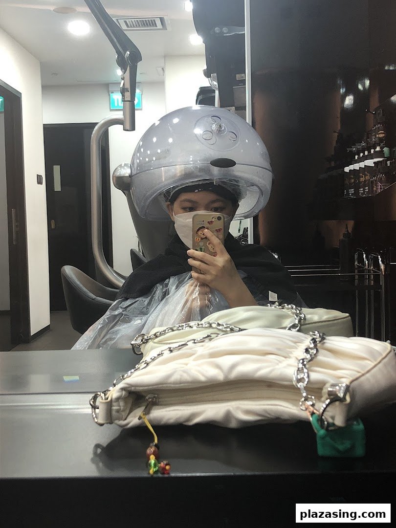 A person in a face mask is reflected in a mirror, undergoing a hair treatment with a steamer at Jonsson Protein.