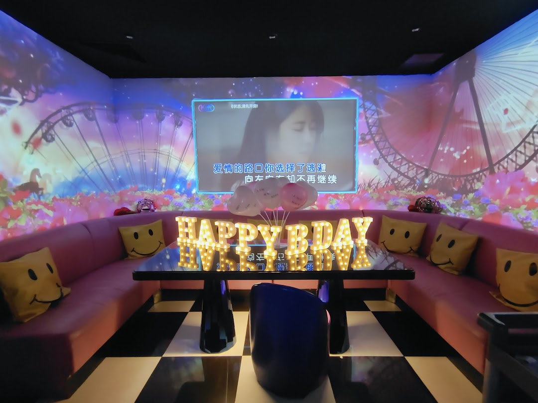 A vibrant KTV room with a large screen, colorful wall projections, and a 'Happy Bday' sign.