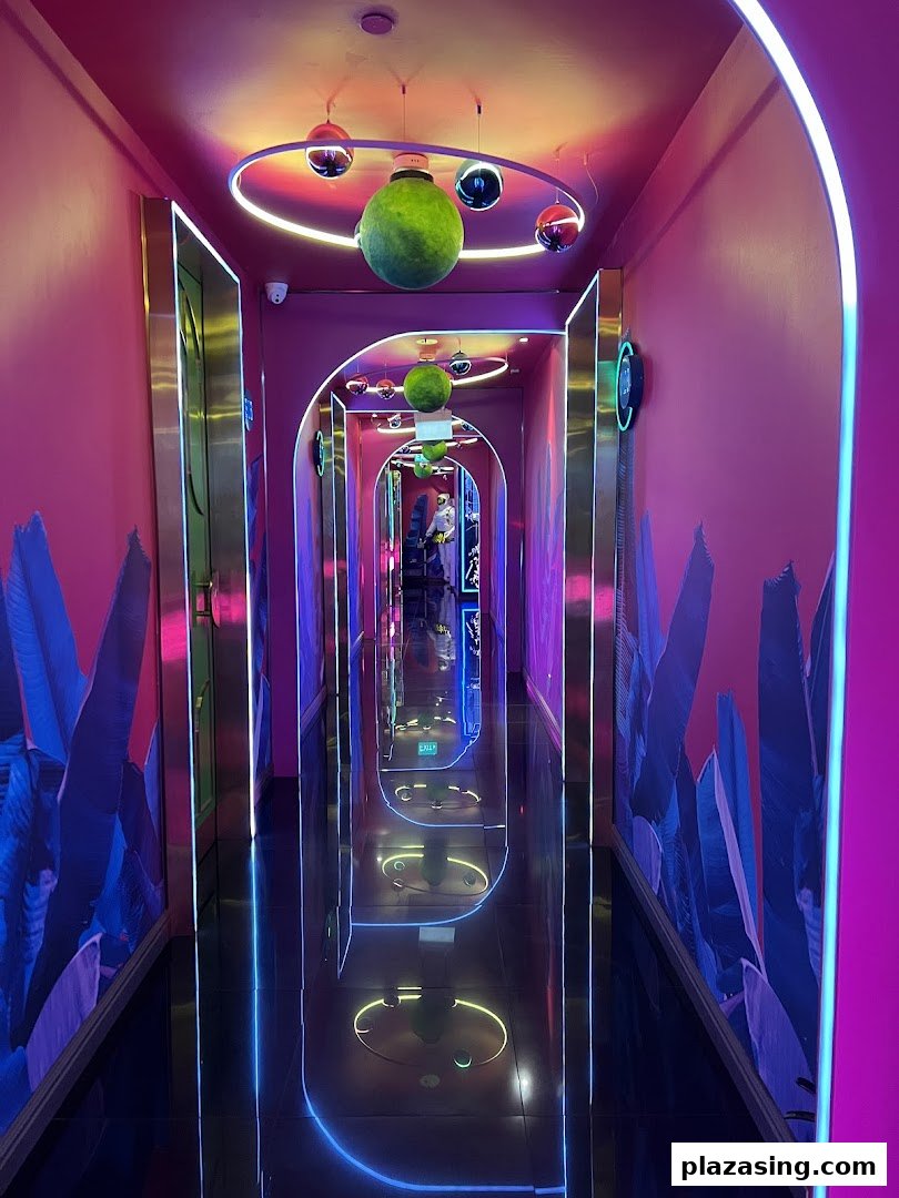 A vibrant, neon-lit hallway with reflective floors leading to KTV rooms.