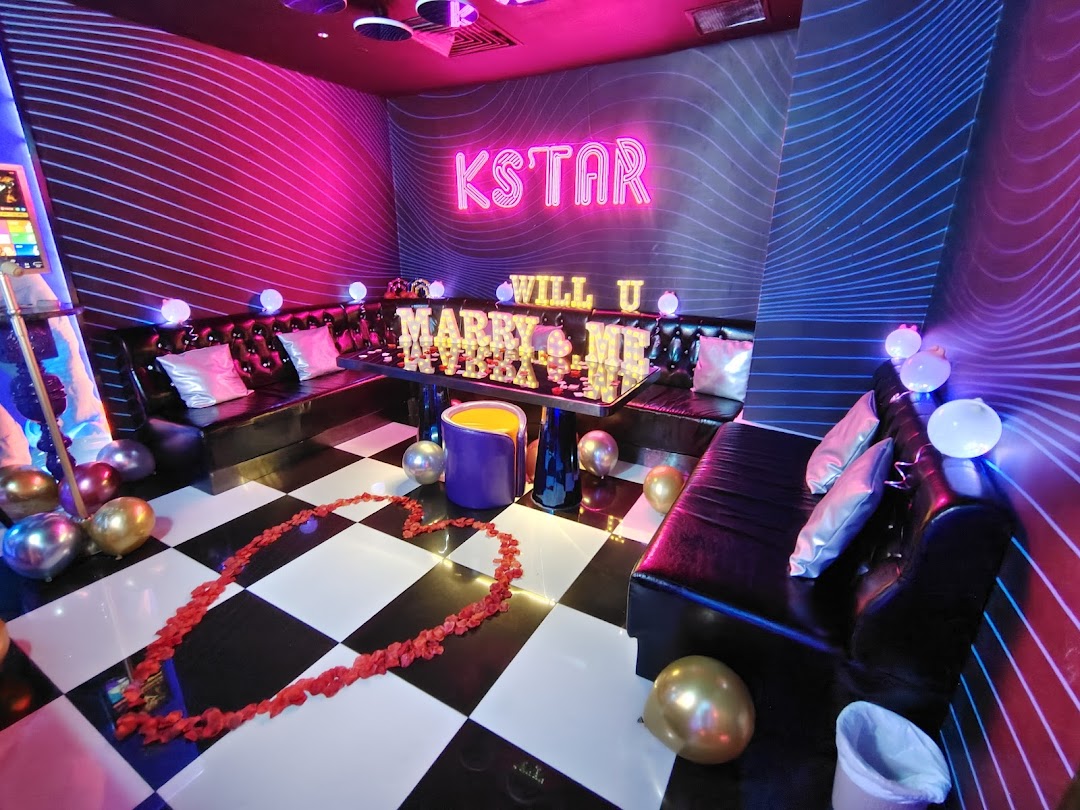 A vibrant KTV room decorated for a proposal with neon lights, balloons, and rose petals.