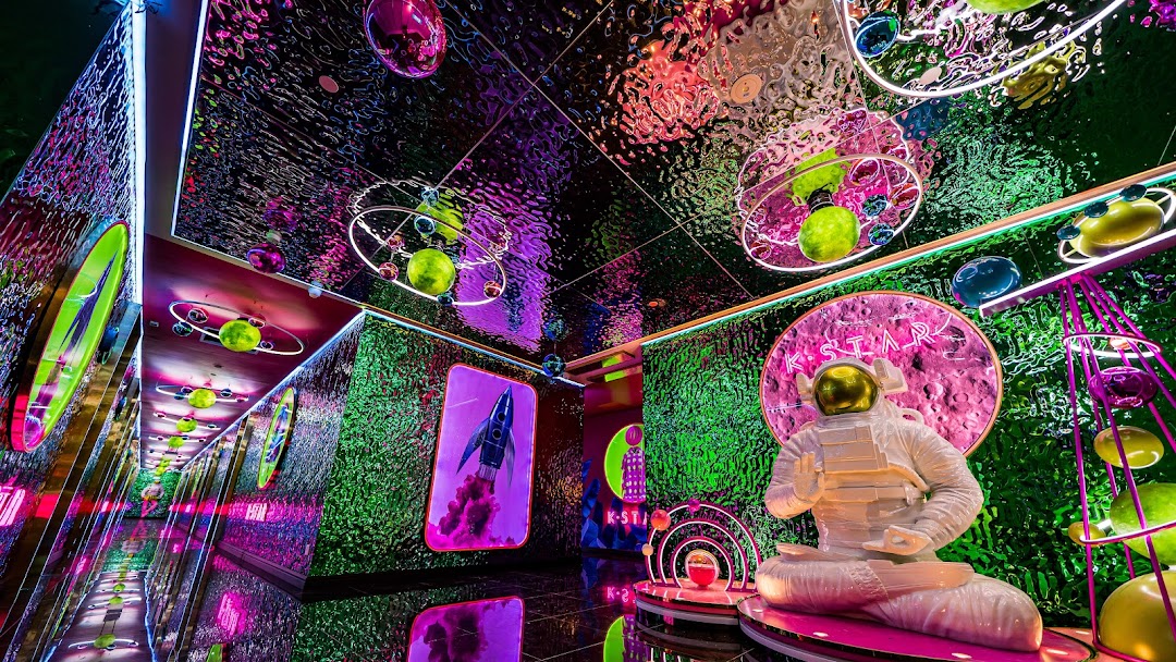 Vibrant, space-themed interior of K.STAR with an astronaut statue and neon lights.