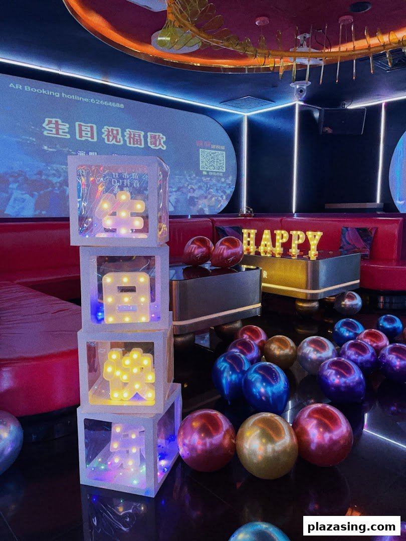 Vibrant KTV room decorated for a celebration with illuminated signs and balloons.