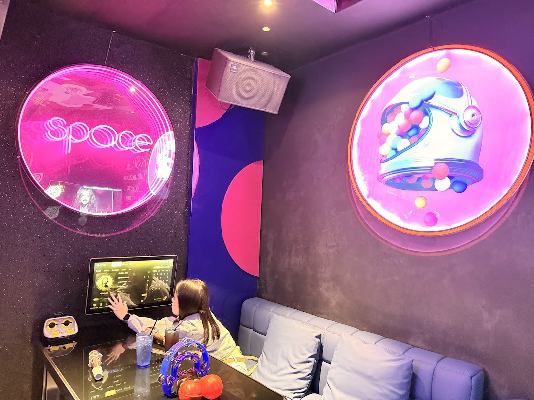 A person selecting songs in a vibrant, space-themed karaoke room at K.STAR.