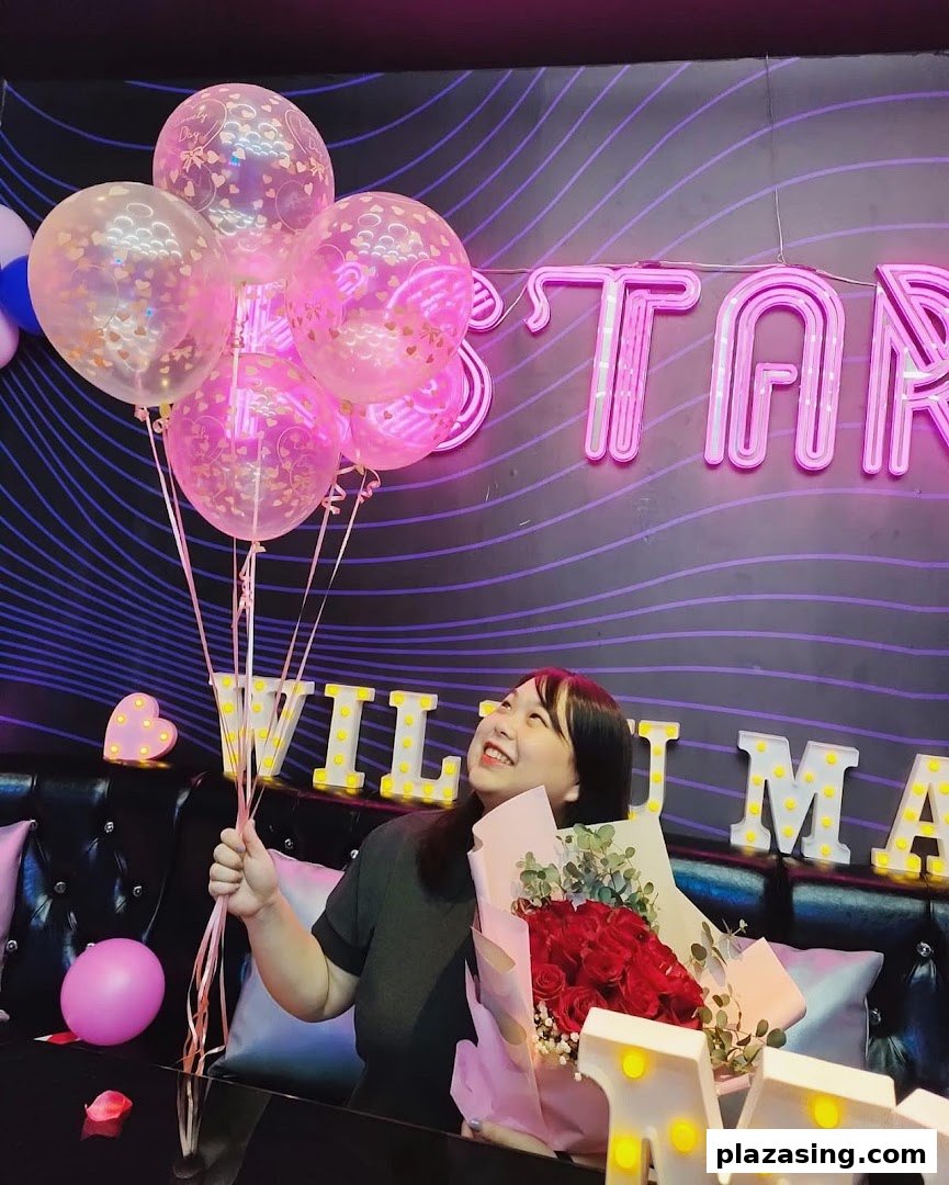 A person celebrating with balloons and a bouquet in a vibrant K.STAR KTV room.