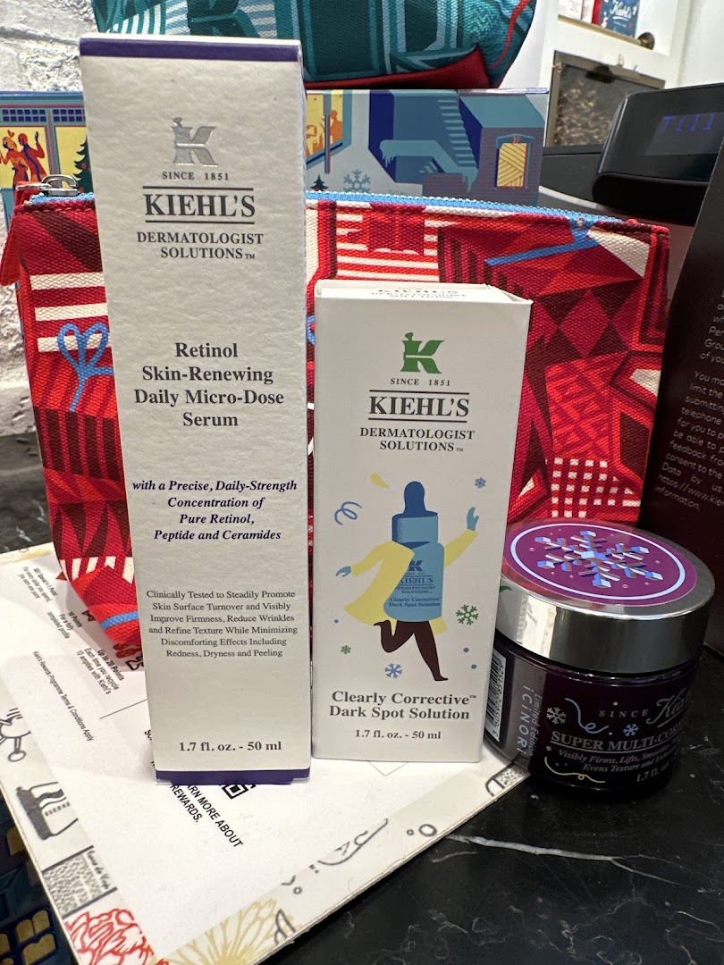 A close-up of Kiehl's skincare products, including serums and a cream, displayed with branded pouches.