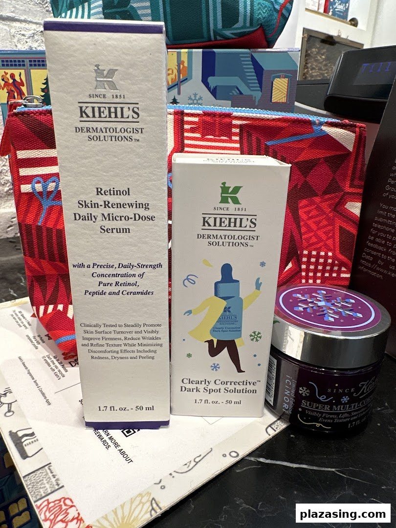 A close-up of Kiehl's skincare products, including serums and a cream, displayed with branded pouches.