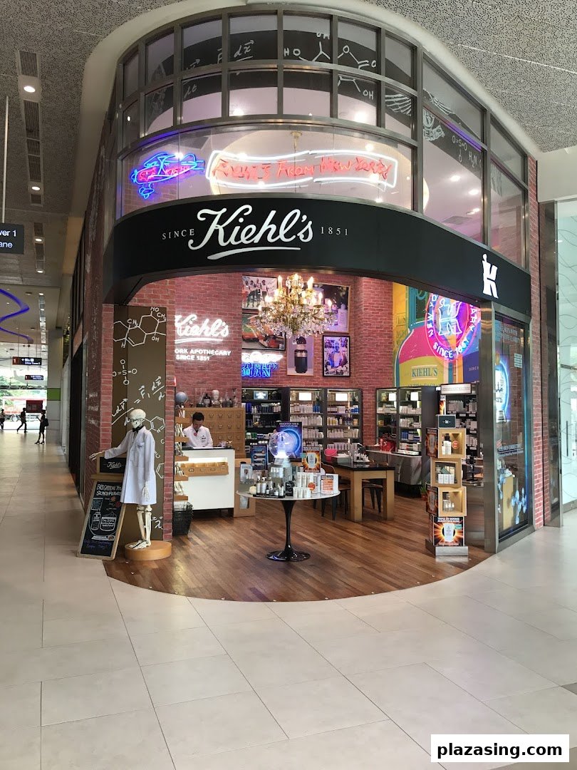 The Kiehl's shop front features a skeleton mascot, neon signs, and a brick wall interior, inviting customers in.