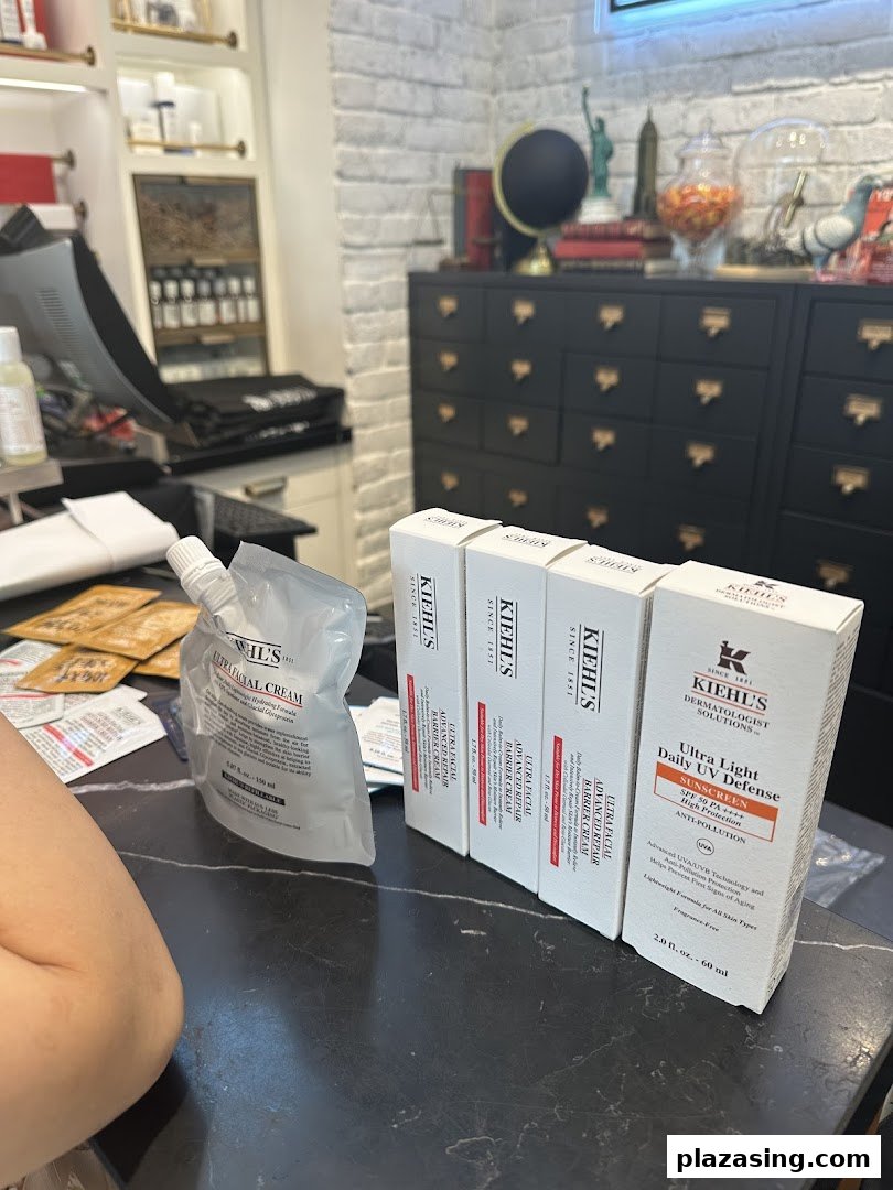 Kiehl's skincare products, including Ultra Facial Cream and UV Defense, displayed on a counter with shop interior.