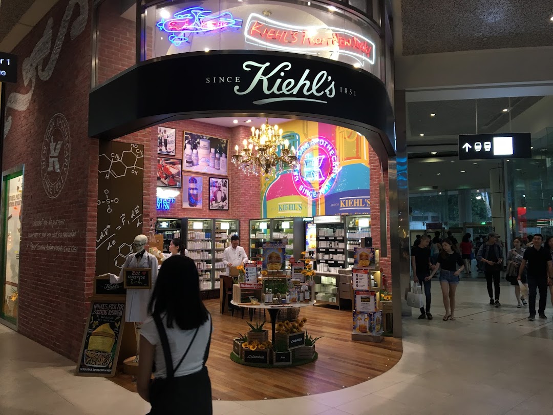 A vibrant Kiehl's store interior showcasing skincare products, a chandelier, and a unique apothecary aesthetic.