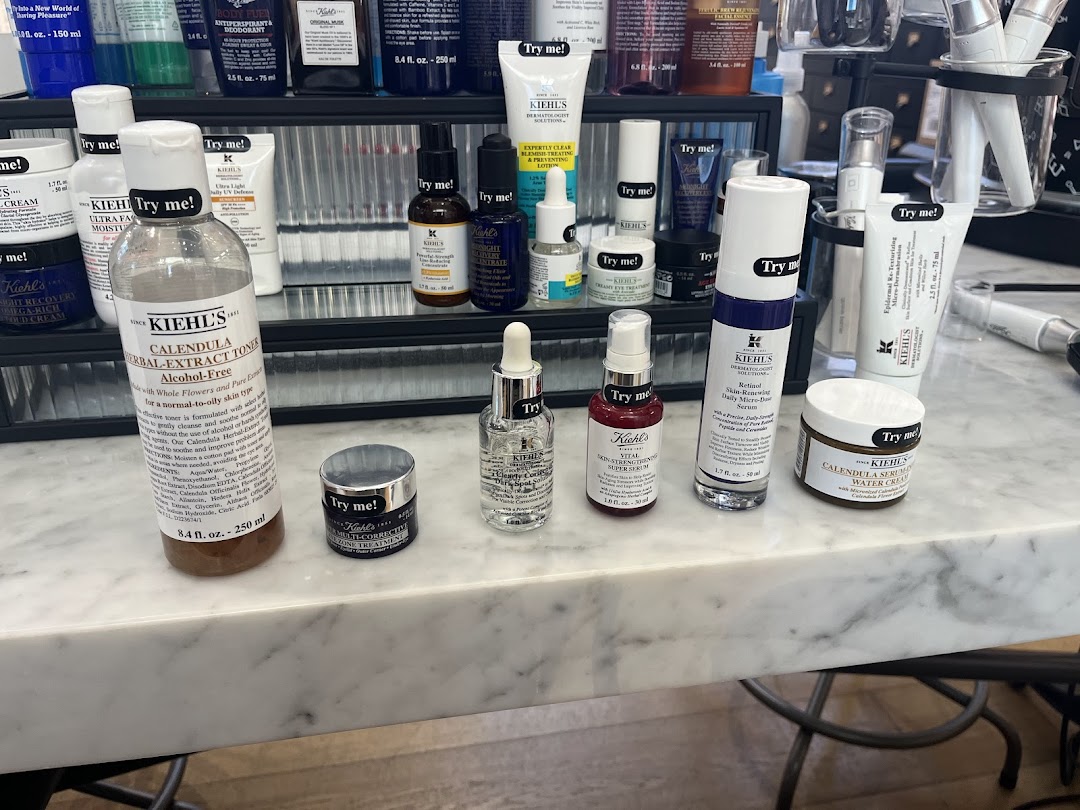 A counter display of various Kiehl's skincare products, many with 'Try me!' labels for sampling.