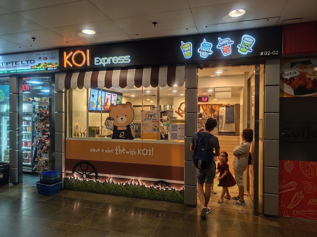 The vibrant KOI Express bubble tea shop front with customers, featuring a cute bear mascot and inviting entrance.