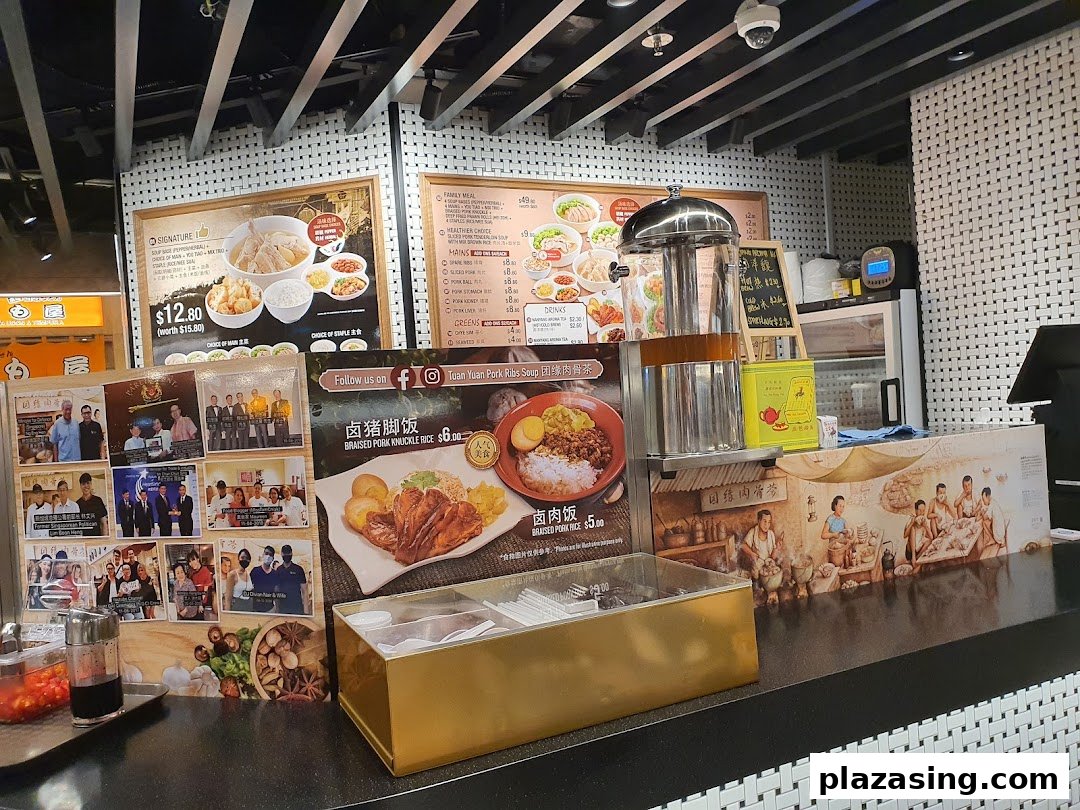 A food stall counter at Kopitiam Food Hall featuring large menu boards and promotional displays.