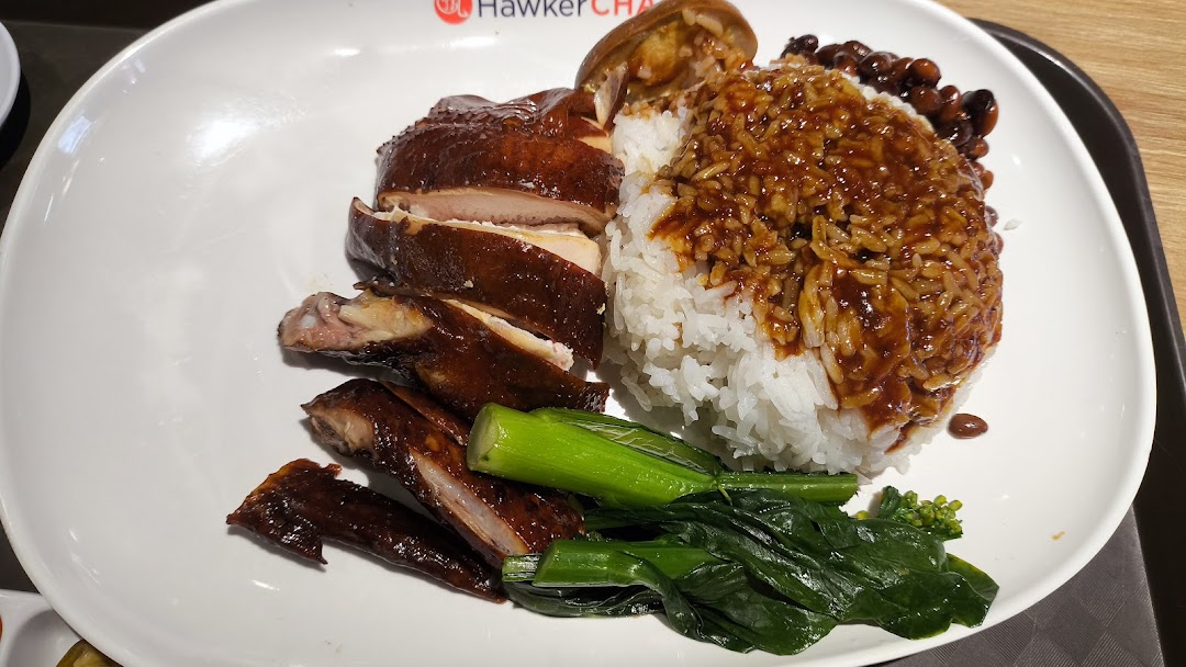 A plate of roasted chicken with rice, sauce, and green vegetables, likely from Hawker Chan.