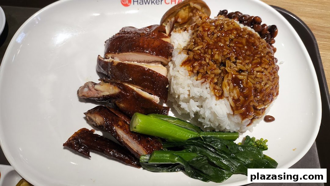 A plate of roasted chicken with rice, sauce, and green vegetables, likely from Hawker Chan.