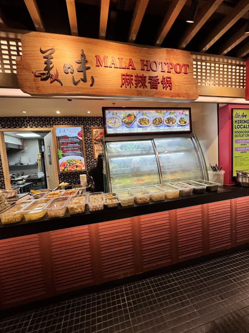 A Mala Hotpot stall counter displaying fresh ingredients and a menu board in a food hall.