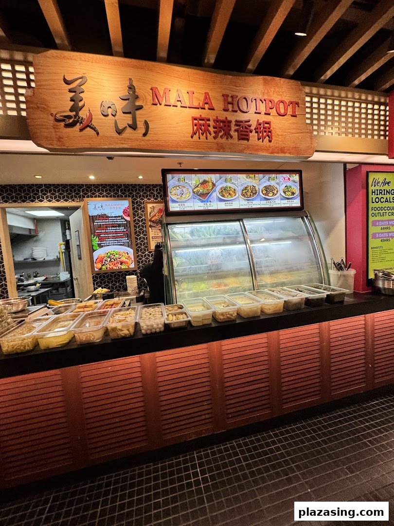 A Mala Hotpot stall counter displaying fresh ingredients and a menu board in a food hall.