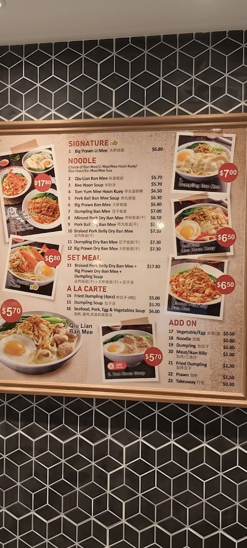 A detailed menu board displaying various noodle dishes, set meals, and add-ons with prices.