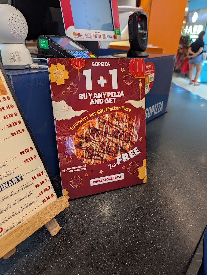 A GOPIZZA 1+1 promotion for Hot BBQ Chicken Pizza displayed at a food hall counter.