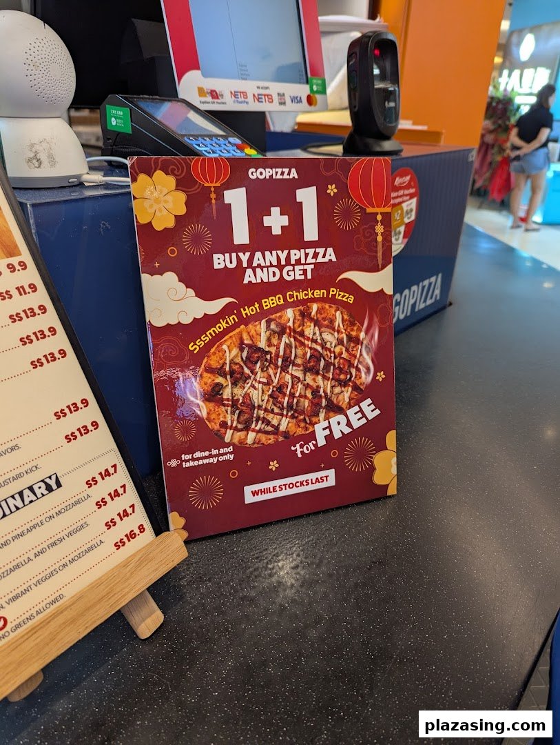 A GOPIZZA 1+1 promotion for Hot BBQ Chicken Pizza displayed at a food hall counter.