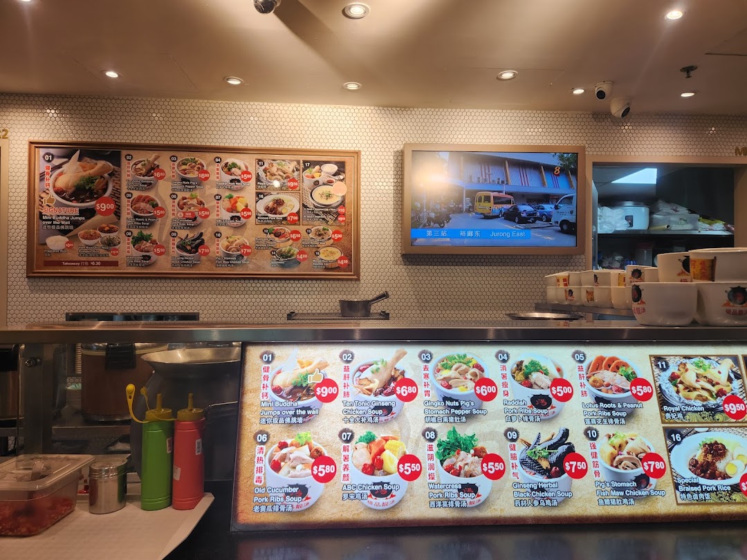 A food stall counter displaying various traditional Chinese soup and rice dishes on illuminated menu boards.