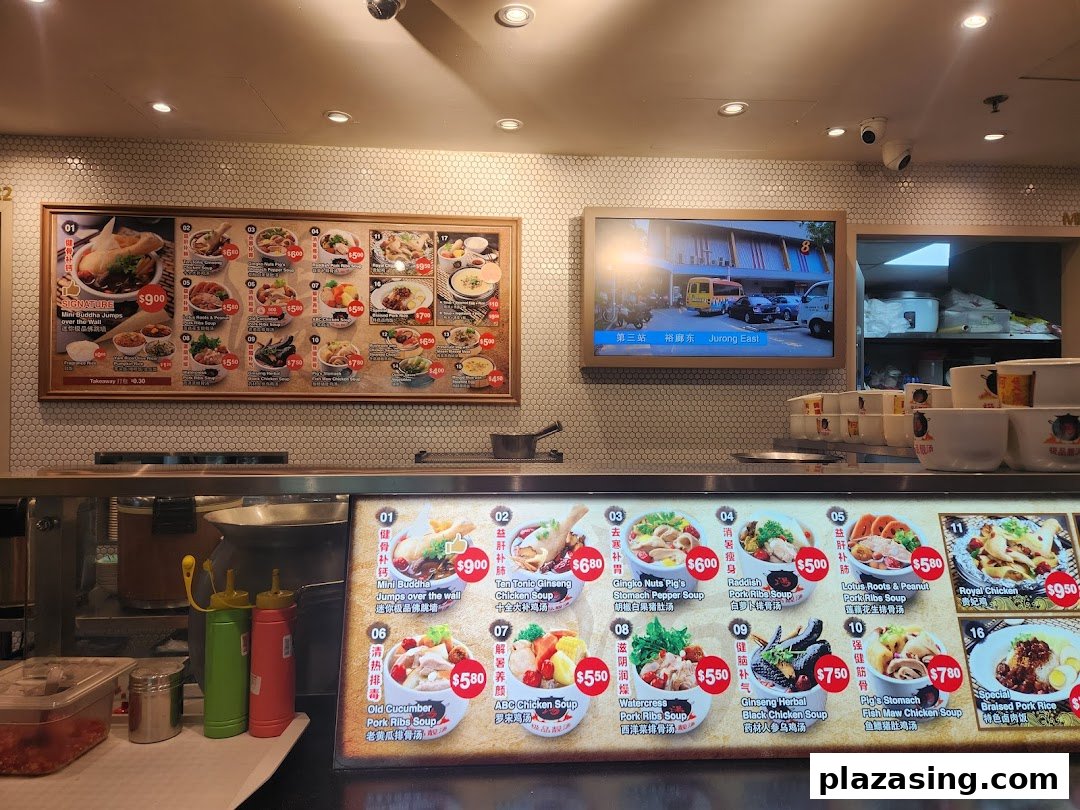 A food stall counter displaying various traditional Chinese soup and rice dishes on illuminated menu boards.