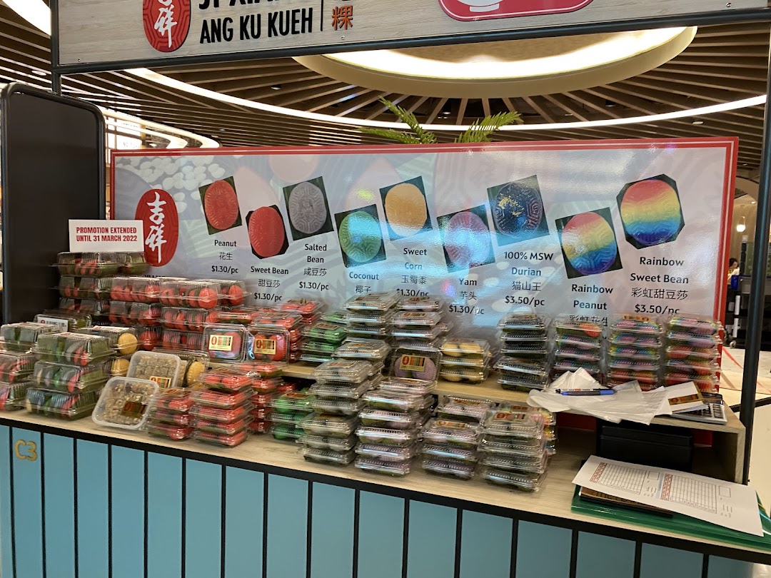A vibrant stall displaying various traditional Ang Ku Kueh pastries with flavor options and prices.