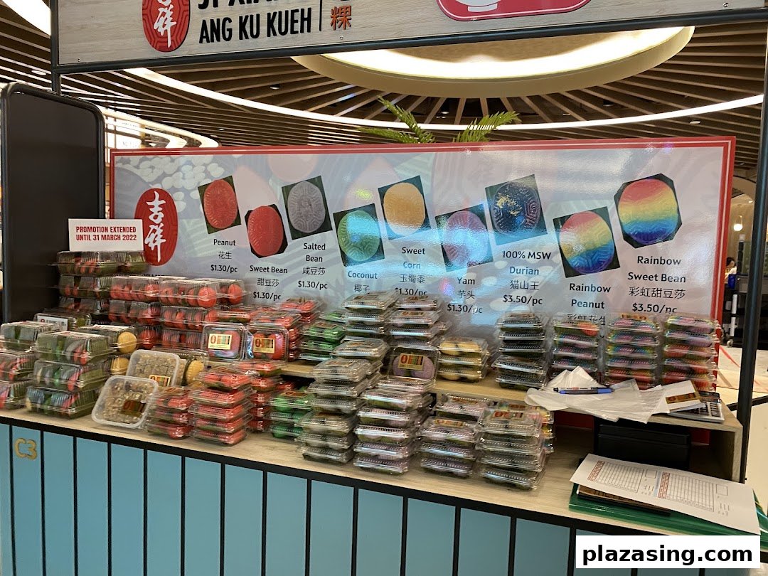 A vibrant stall displaying various traditional Ang Ku Kueh pastries with flavor options and prices.