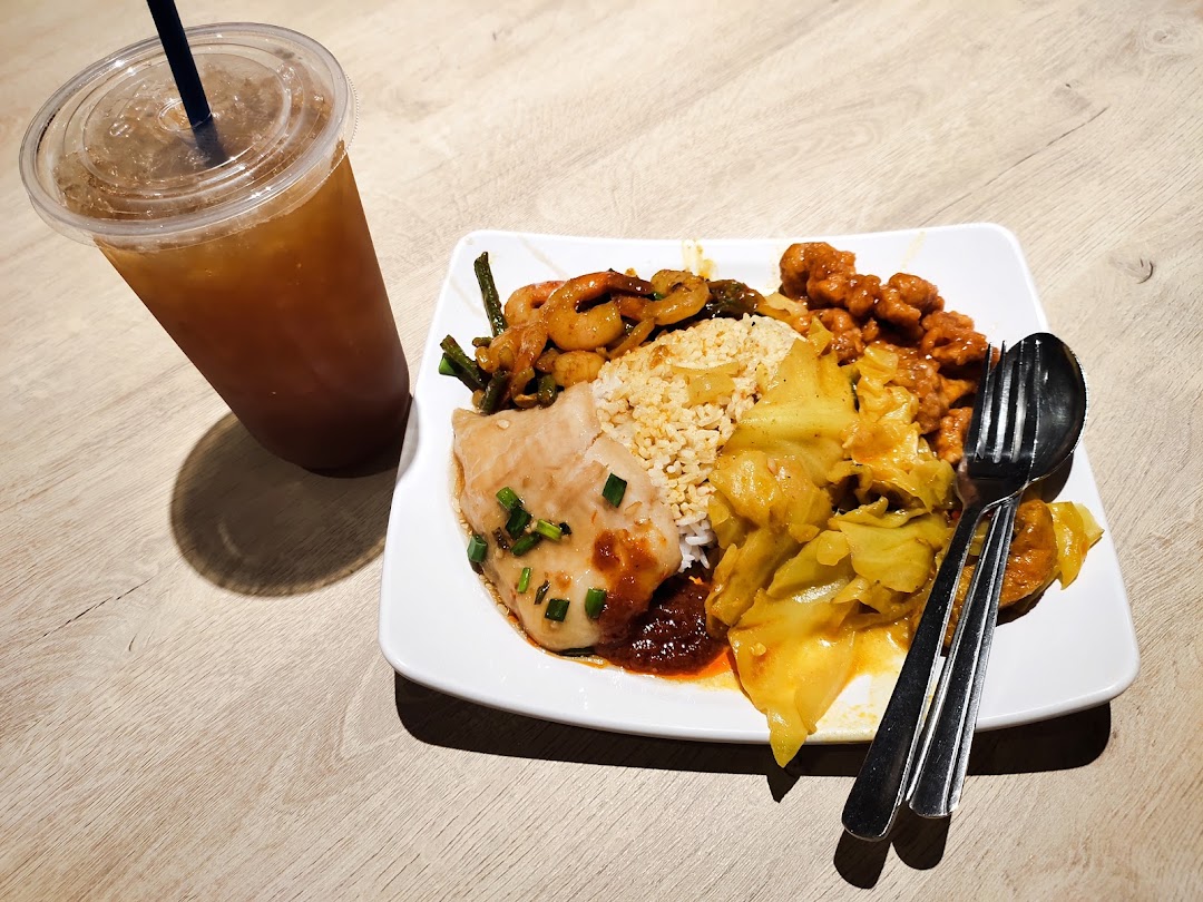 A plate of diverse Asian dishes with rice and a cold drink on a wooden table.