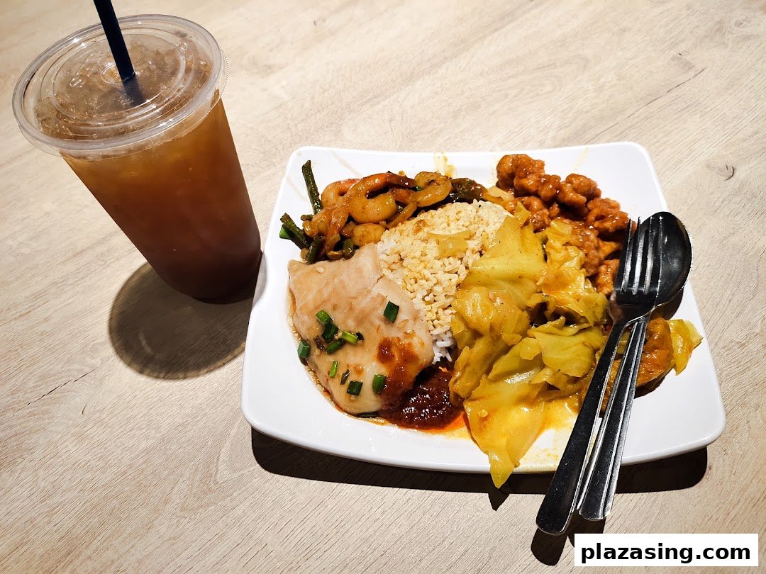 A plate of diverse Asian dishes with rice and a cold drink on a wooden table.
