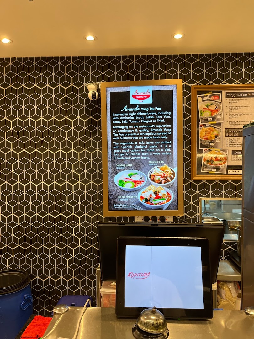 An interior view of Kopitiam Food Hall featuring a Yong Tau Foo descriptive menu board and a POS system.