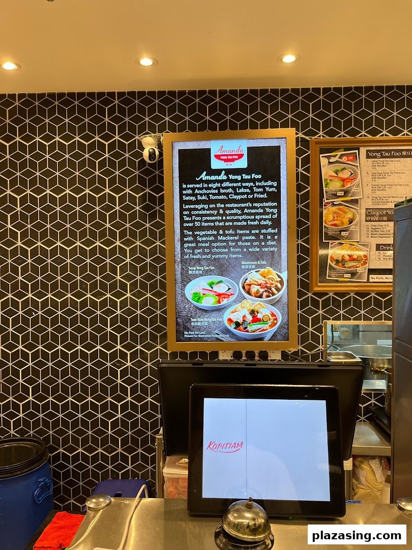 An interior view of Kopitiam Food Hall featuring a Yong Tau Foo descriptive menu board and a POS system.