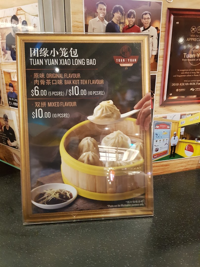 A framed menu display for Tuan Yuan Xiao Long Bao, showcasing various dumpling flavors and prices.