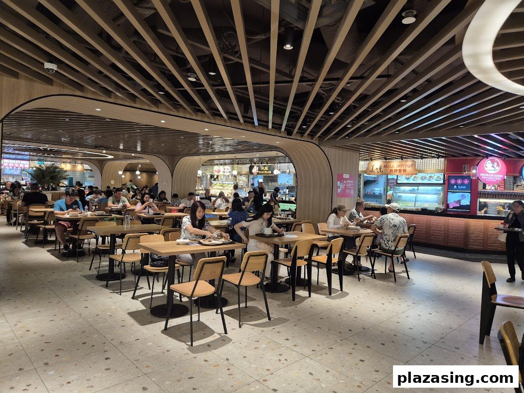 A bustling food hall interior with numerous diners enjoying meals at various food stalls.