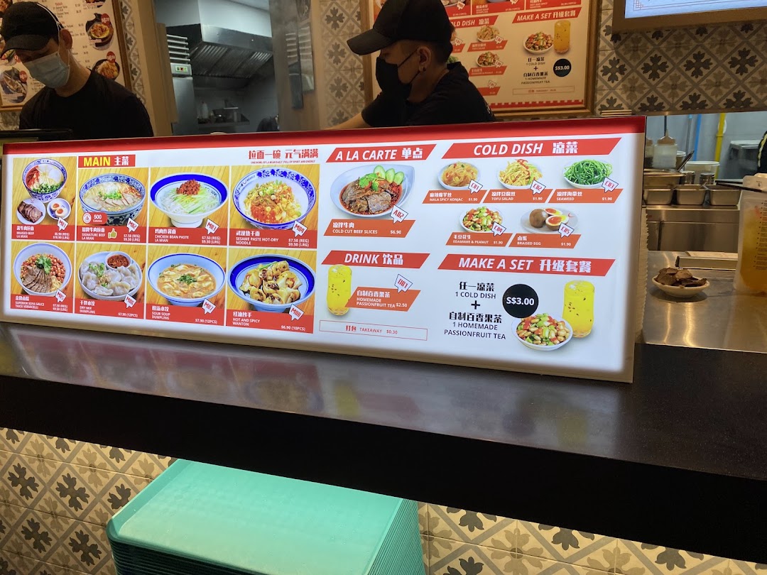 A brightly lit menu board displaying various Asian dishes and drinks at Kopitiam Food Hall.