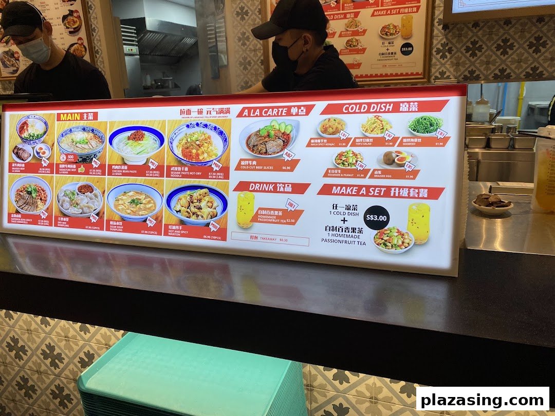A brightly lit menu board displaying various Asian dishes and drinks at Kopitiam Food Hall.