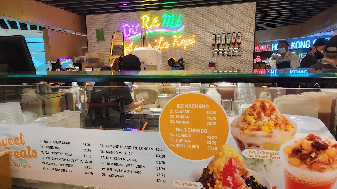 A food stall counter displaying a menu for traditional Asian desserts like Ice Kachang and Chendol.